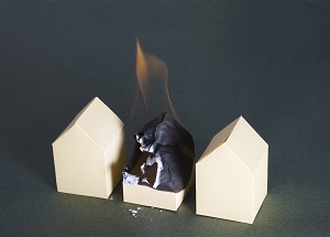 paper houses with one in the middle on fire